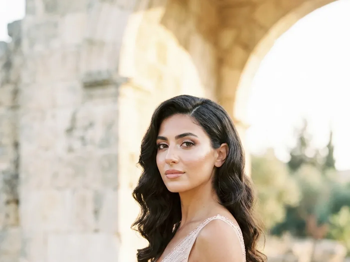A bride smiling softly in daylight, her makeup beautiful and natural, letting her own features shine through.